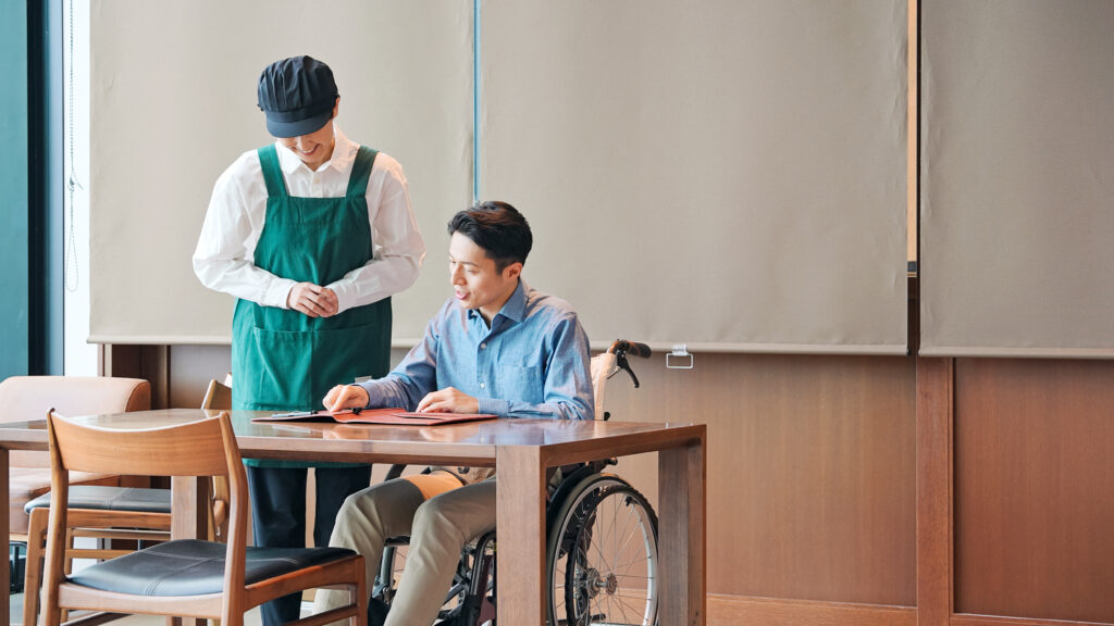 車いす、車椅子、バリアフリー、レストラン、飲食店、店員、スタッフ、接客、注文、メニュー、オーダー、サポート、障害者、お客様、バリアフル、女性、エプロン、日本人、仕事、アルバイト、パート、職場、カフェ、ファストフード、ショップ、室内、接客業、男性、テーブル、挨拶、人材、入店可、対応、予約、支援、優しい、優しさ、おもてなし、笑顔、真心、介護、働く、福祉、ウェルネス、ヘルパー、着席、サービス、顧客、人物